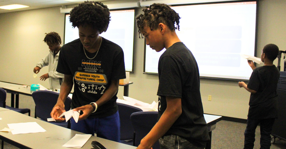two male students building paper airplane